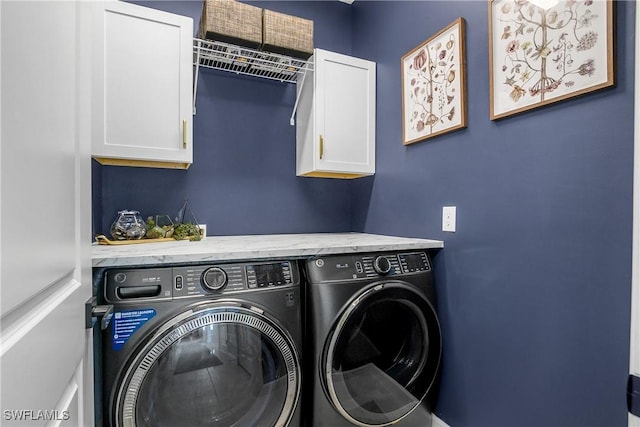 clothes washing area with washer and dryer and cabinets