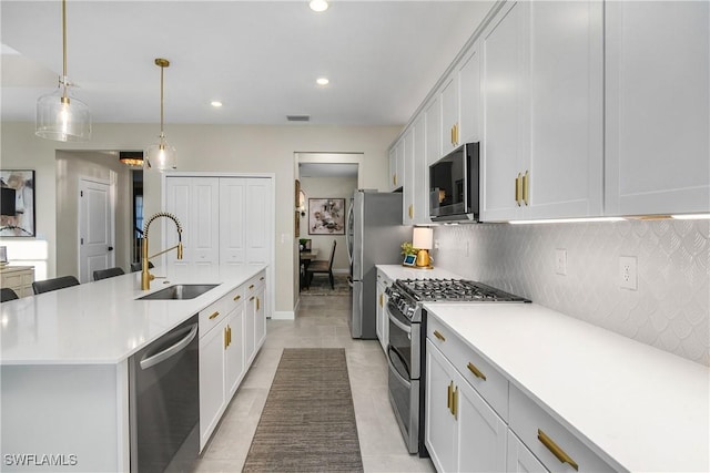 kitchen with appliances with stainless steel finishes, an island with sink, white cabinets, and sink