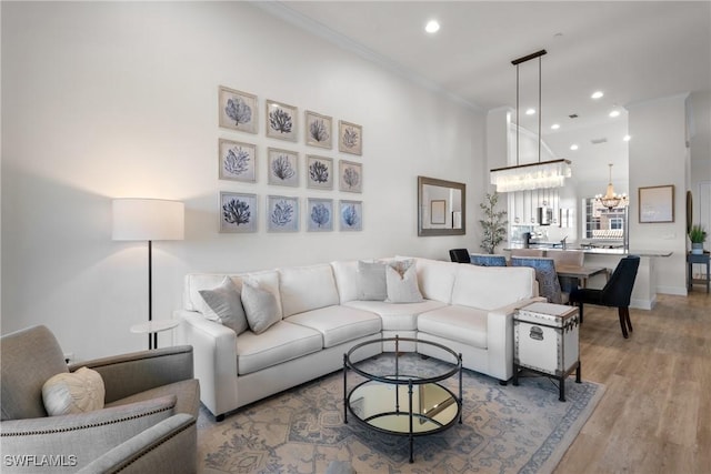 living room with crown molding, wood-type flooring, and an inviting chandelier