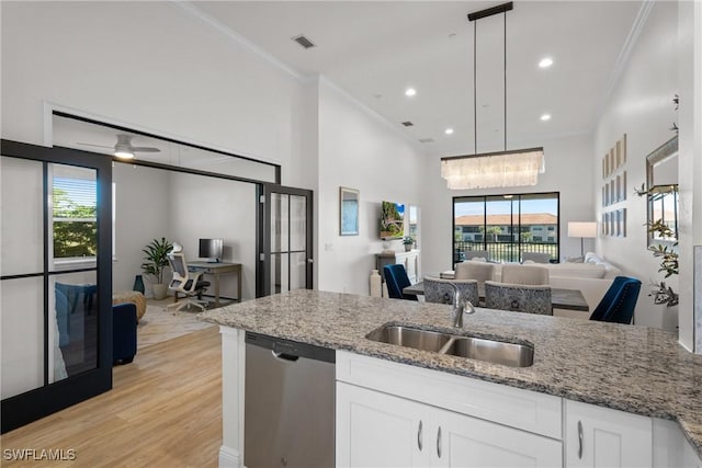 kitchen featuring pendant lighting, white cabinets, sink, stainless steel dishwasher, and light stone countertops