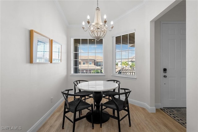 dining area with light hardwood / wood-style floors, ornamental molding, and a notable chandelier