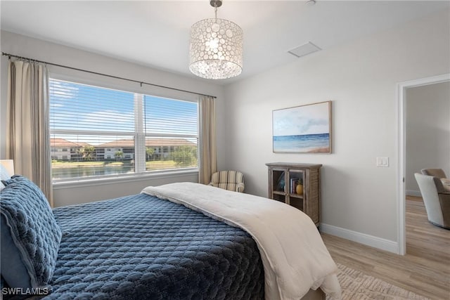 bedroom with hardwood / wood-style floors and a water view