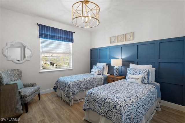 bedroom with light hardwood / wood-style flooring and an inviting chandelier