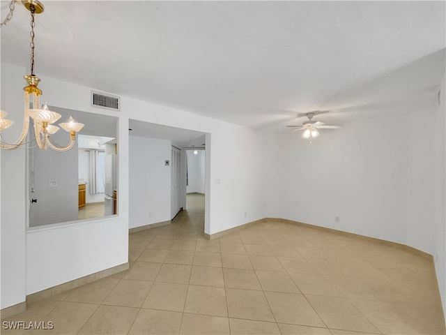 spare room featuring light tile patterned floors and ceiling fan with notable chandelier