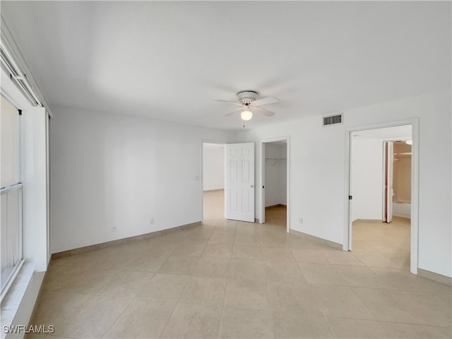 unfurnished bedroom featuring a closet, a spacious closet, and ceiling fan