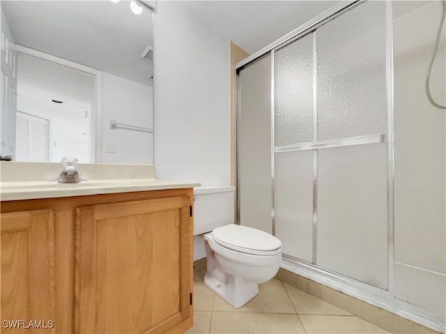 bathroom featuring tile patterned flooring, vanity, toilet, and an enclosed shower