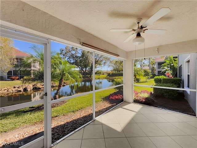 unfurnished sunroom with ceiling fan, a healthy amount of sunlight, and a water view