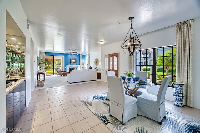 tiled dining area with ceiling fan with notable chandelier