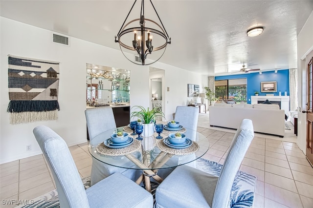 dining area featuring light tile patterned floors and ceiling fan with notable chandelier