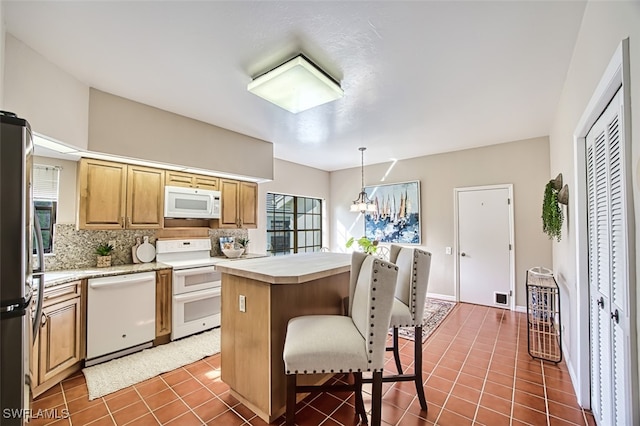 kitchen featuring white appliances, hanging light fixtures, a kitchen island, dark tile patterned flooring, and decorative backsplash