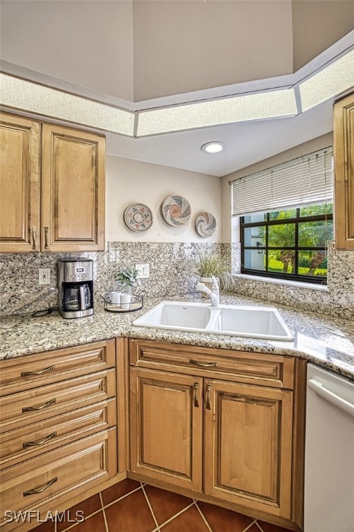 kitchen featuring dark tile patterned floors, dishwasher, sink, and backsplash