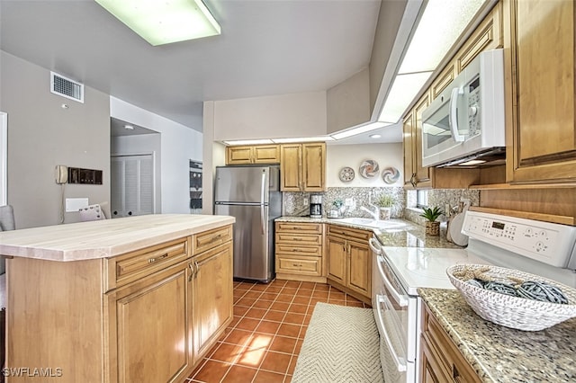 kitchen featuring a kitchen island, sink, backsplash, dark tile patterned flooring, and white appliances