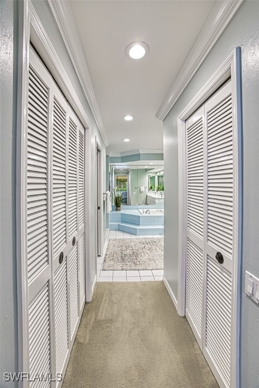 hallway with crown molding and light colored carpet