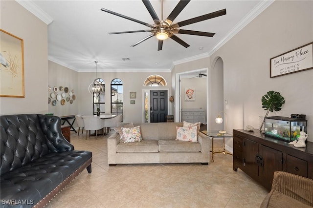 tiled living room with ceiling fan with notable chandelier and crown molding