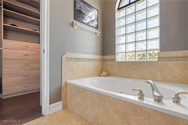 bathroom featuring tile patterned flooring and a relaxing tiled tub