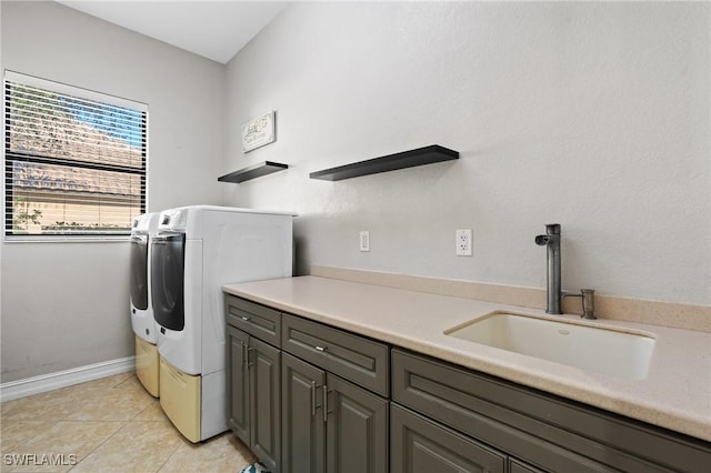 laundry room featuring sink, washing machine and clothes dryer, light tile patterned floors, and cabinets