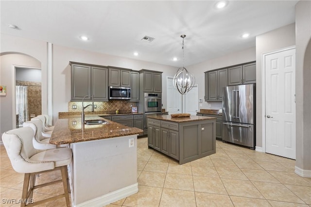 kitchen featuring stainless steel appliances, sink, dark stone countertops, pendant lighting, and gray cabinetry