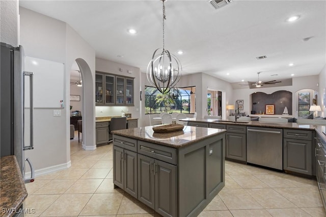 kitchen with decorative light fixtures, stainless steel appliances, a kitchen island, gray cabinets, and dark stone countertops