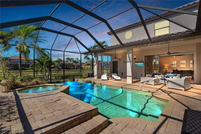 pool at dusk with a lanai, a patio, an in ground hot tub, and an outdoor living space