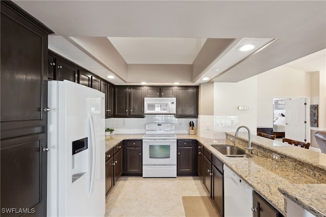 kitchen with white appliances, sink, tasteful backsplash, light stone counters, and kitchen peninsula