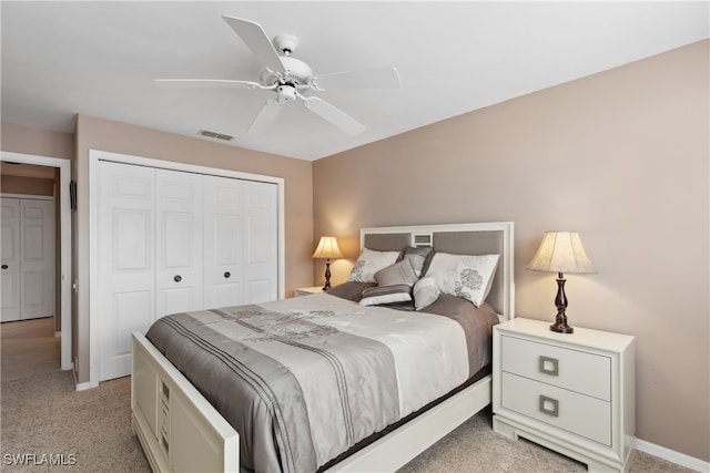 bedroom with ceiling fan, light colored carpet, and a closet