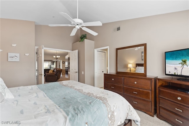 bedroom featuring ceiling fan with notable chandelier, light colored carpet, and lofted ceiling