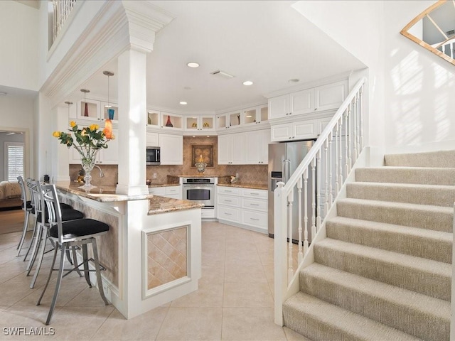 kitchen featuring backsplash, white cabinetry, kitchen peninsula, and stainless steel appliances