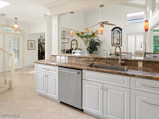 kitchen with decorative columns, stainless steel dishwasher, sink, white cabinetry, and hanging light fixtures