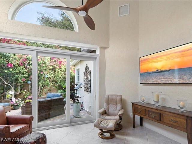 interior space featuring ceiling fan, a towering ceiling, and light tile patterned flooring