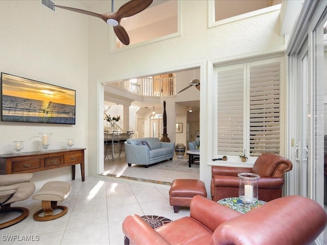 living room featuring ornate columns, ceiling fan, a towering ceiling, and light tile patterned floors