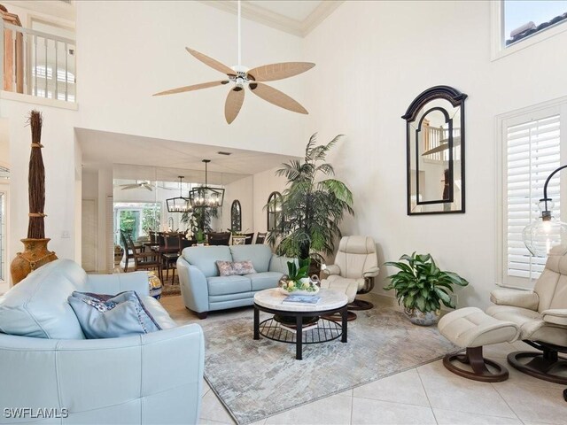 tiled living room with ceiling fan with notable chandelier and a towering ceiling