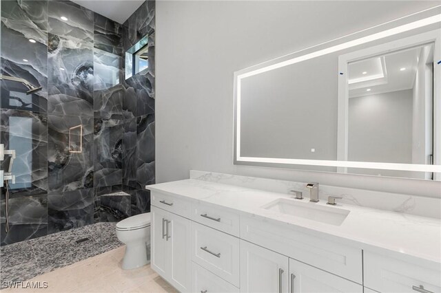 bathroom with a tile shower, toilet, recessed lighting, and vanity