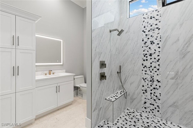 bathroom featuring vanity, toilet, and tiled shower