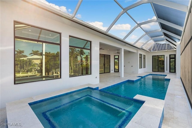 view of swimming pool with a pool with connected hot tub, glass enclosure, ceiling fan, and a patio