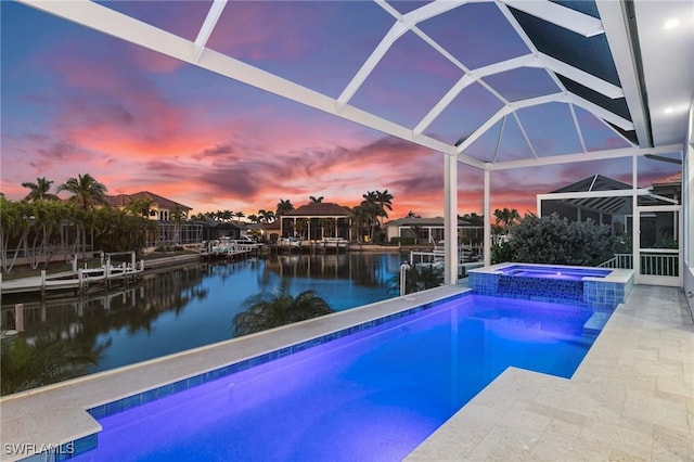 pool at dusk featuring an in ground hot tub, a lanai, a water view, and a patio area