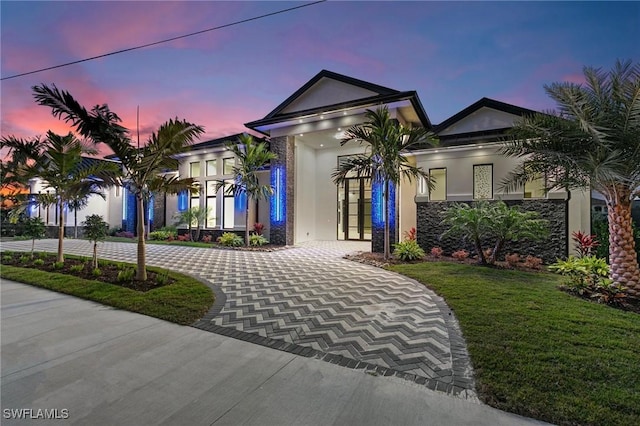 view of front of house with stucco siding, a front lawn, and curved driveway
