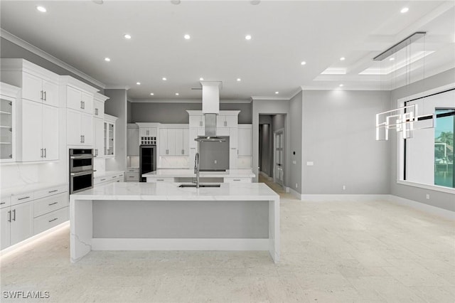 kitchen with white cabinetry, a spacious island, hanging light fixtures, light stone countertops, and sink