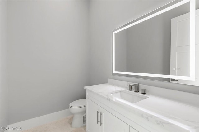 half bathroom featuring baseboards, toilet, and vanity