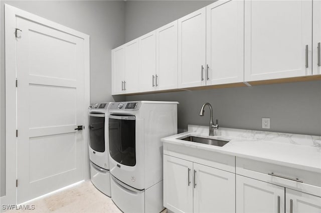 laundry area with sink, washing machine and clothes dryer, and cabinets