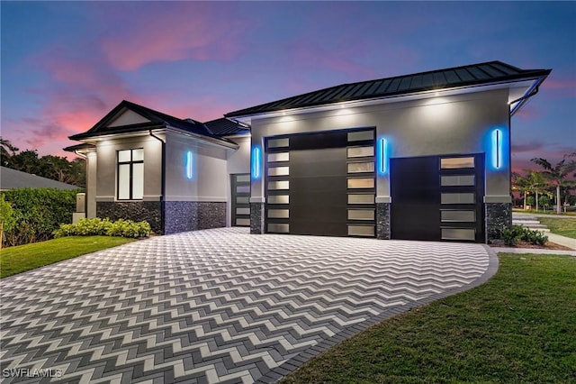 view of front facade featuring a standing seam roof, stucco siding, stone siding, decorative driveway, and metal roof