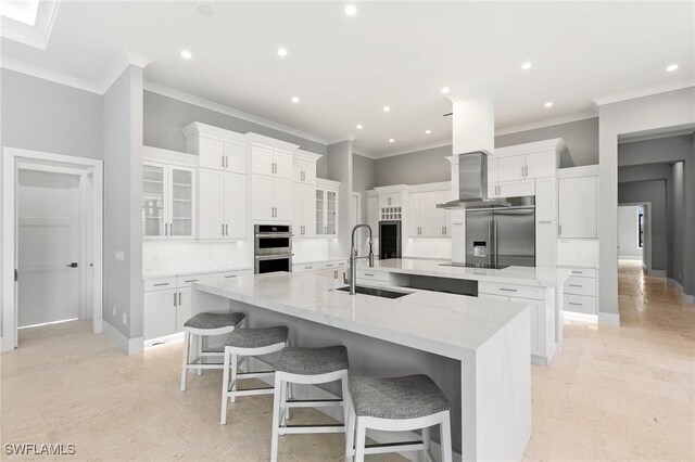 kitchen featuring a large island, a sink, appliances with stainless steel finishes, white cabinets, and island range hood