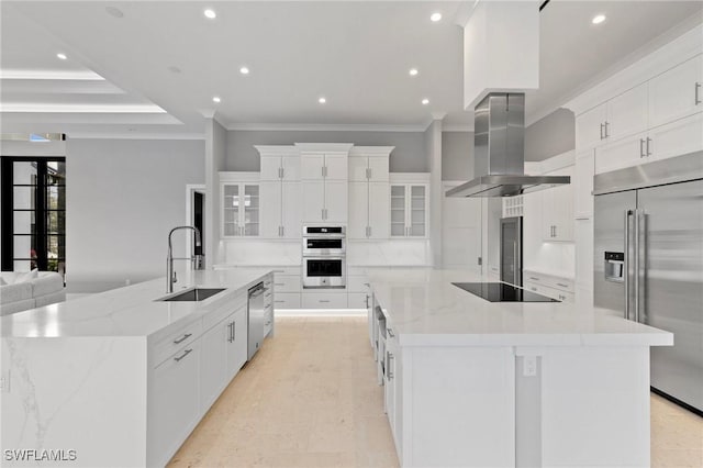 kitchen featuring ornamental molding, a sink, stainless steel appliances, wall chimney exhaust hood, and a large island with sink