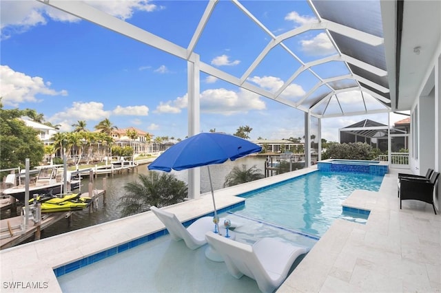view of pool featuring glass enclosure, a pool with connected hot tub, a water view, and a patio area
