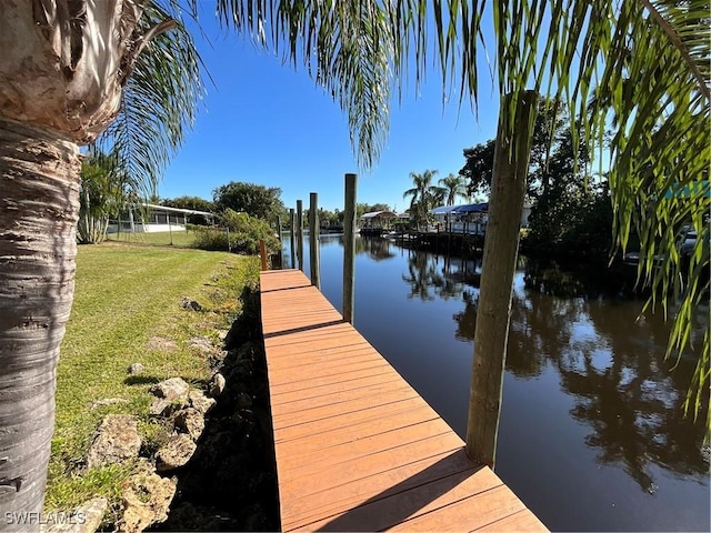 dock area with a lawn and a water view