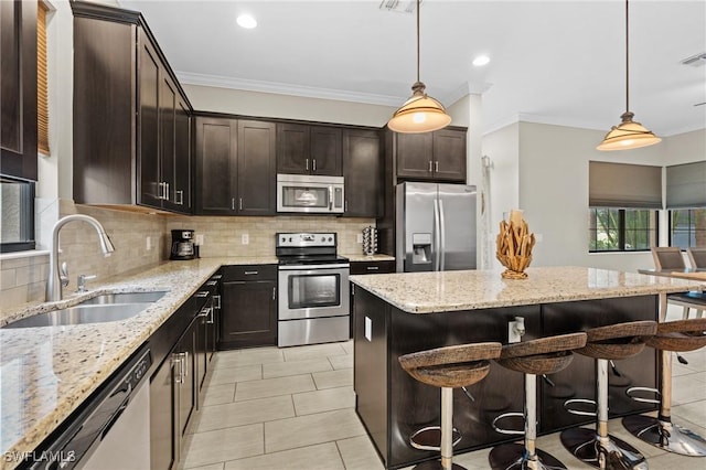 kitchen featuring a kitchen breakfast bar, appliances with stainless steel finishes, hanging light fixtures, and sink