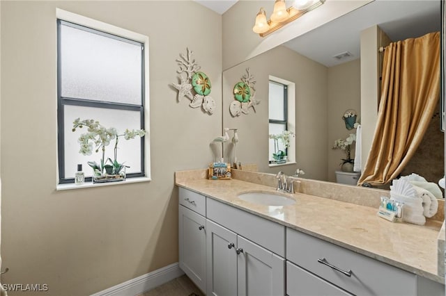 bathroom featuring a healthy amount of sunlight, vanity, and toilet