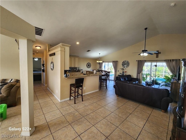 living room with lofted ceiling, light tile patterned floors, and ceiling fan with notable chandelier