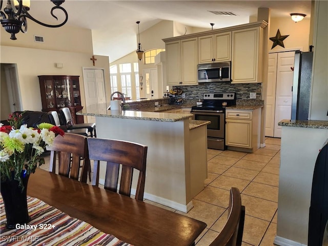 kitchen with stainless steel appliances, light stone countertops, cream cabinets, and decorative light fixtures