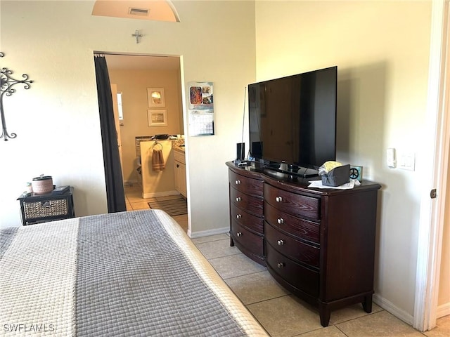 bedroom with ensuite bathroom and light tile patterned floors