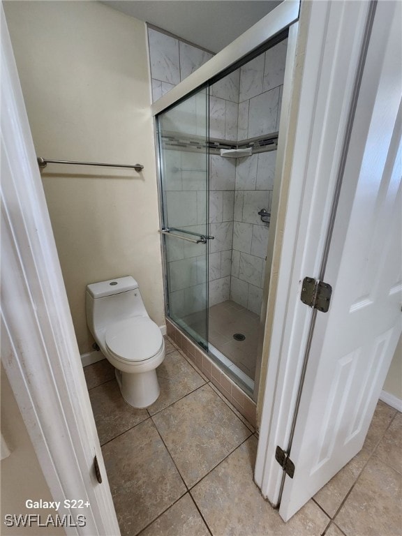 bathroom featuring a shower with door, tile patterned floors, and toilet